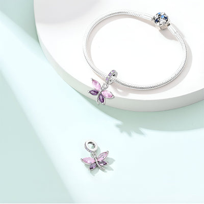 Bracelet argenté avec pendentif libellule rosée violet orné de cristaux colorés et fermoir à bille bleu.