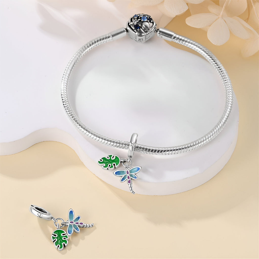Bracelet argent avec charms libellule bleue et feuille verte détaillés.