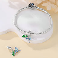Bracelet argent avec charms libellule bleue et feuille verte détaillés.