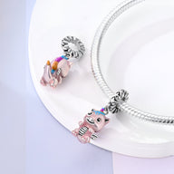 Pendentif licorne volante rose avec ailes et yeux bleus, attaché à une chaîne argentée.