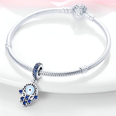 Bracelet argent avec pendentif main de Fatma ornée de pierres bleues et œil protecteur central.