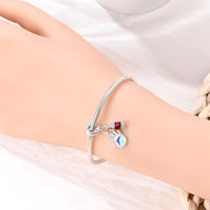 Bracelet argenté avec pendentif main remplie de peinture multicolore et petit drapeau rouge et noir.