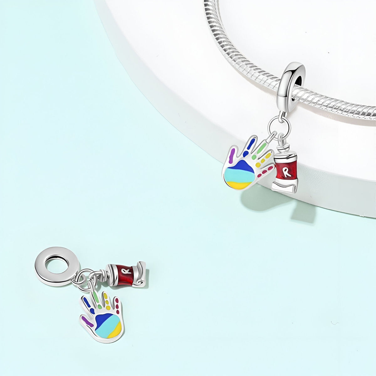 Pendentif charm main colorée remplie de peinture et tube de peinture rouge en argent.