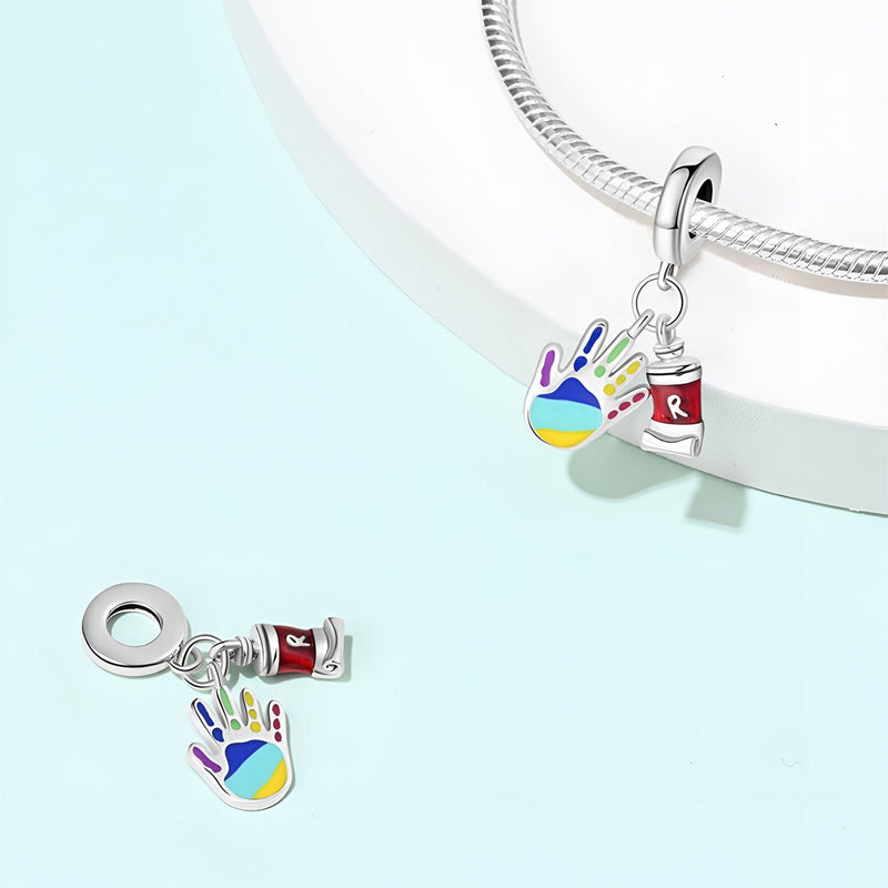 Pendentif charm main colorée remplie de peinture et tube de peinture rouge en argent.
