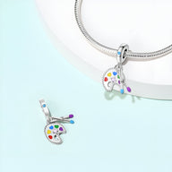 Pendentif palette de peinture en argent avec taches de couleurs vives attaché à un bracelet en métal argenté.