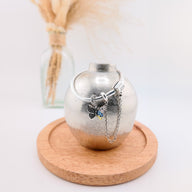 Charm pendentif papillon en argent avec ailes ornées de fleurs colorées, suspendu à une chaîne fine.