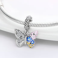 Pendentif papillon argent avec ailes fleurie rose, bleue et jaune sur bracelet serpent en argent.