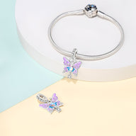 Charm pendentif papillon en métal argenté avec cristaux multicolores, design délicat et brillant.