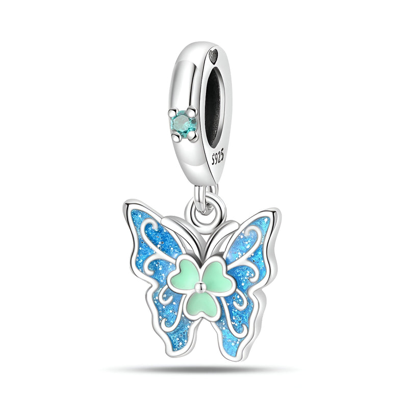 Pendentif charm papillon en argent avec ailes bleues et détail cœur vert pâle.