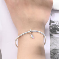 Bracelet argenté avec charm perroquet coloré suspendu au poignet féminin.