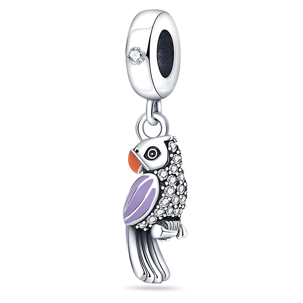 Pendentif charme perroquet en argent avec ailes violettes et détails orange et noirs, orné de pierres blanches brillantes.