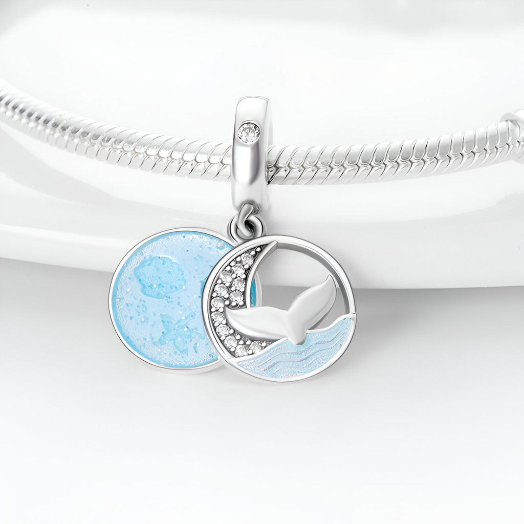 Charm pendentif argent avec queue de baleine et cercle bleu océan texturé sur bracelet serpent.