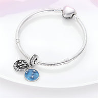 Bracelet argent avec pendentifs lune argentée et médaillon bleu étoiles, fermoir cœur lisse.