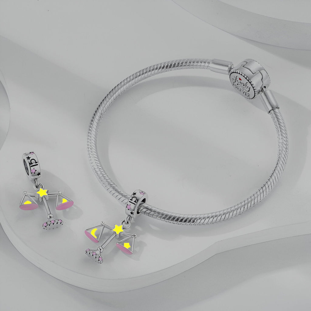 Bracelet argenté avec pendant signe zodiaque Balance orné d'étoiles jaunes et détails roses.