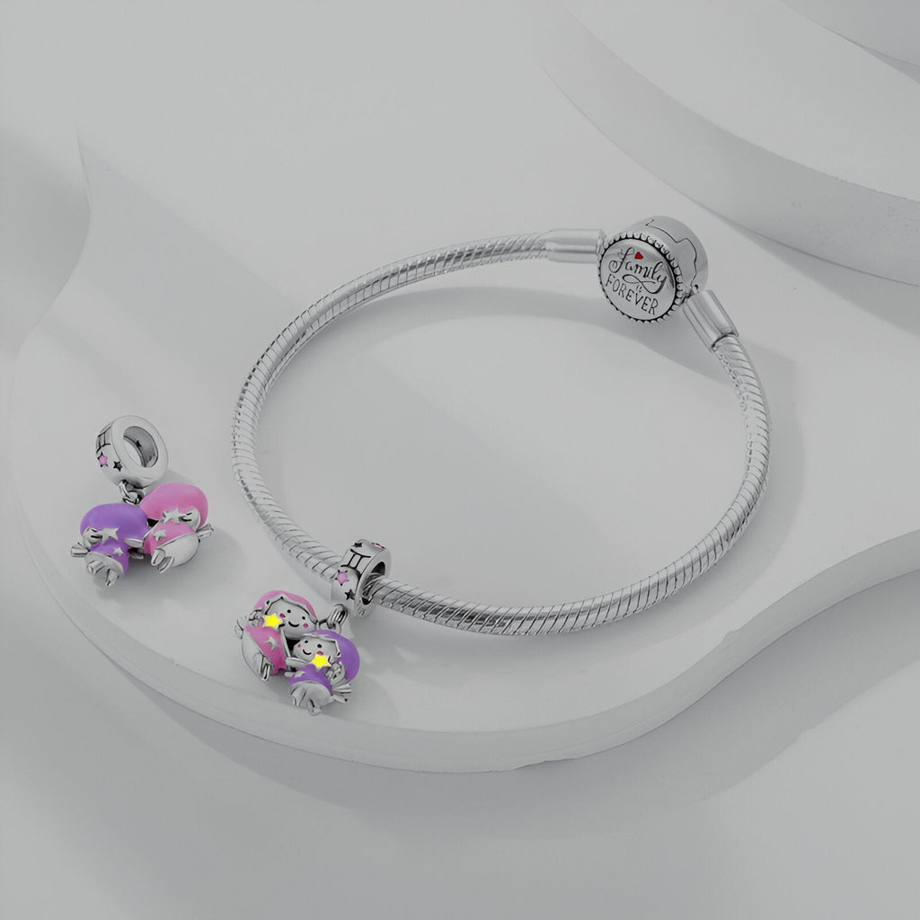 Bracelet argenté rigide avec pendentif signe Gémeaux rose et violet décoré de cristaux éclatants.