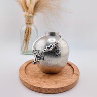 Pendentif argenté charme soleil et lune avec détails ciselés sur support en bois rond.