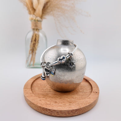 Pendentif argenté charme soleil et lune avec détails ciselés sur support en bois rond.