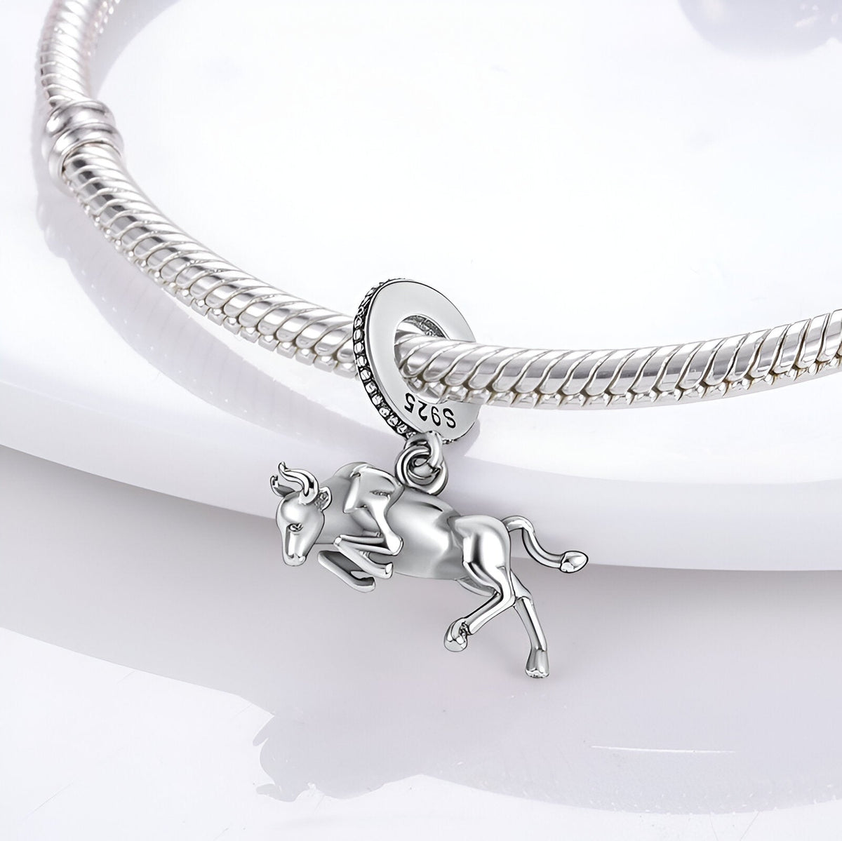 Charm pendentif taureau sprintant en argent poli suspendu à un bracelet serpent argenté.