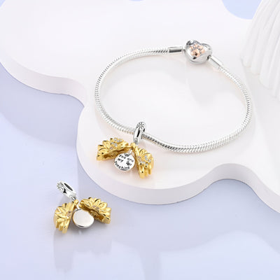 Charm pendentif tournesol doré et argenté avec strass, porté sur bracelet argenté serpent.