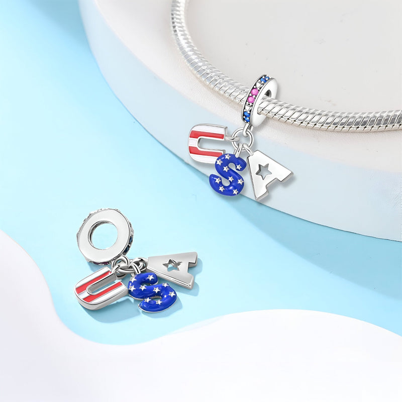 Charm pendentif U.S.A en métal argenté avec drapeau américain et lettres colorées rouge, blanc et bleu.