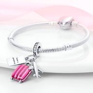 Bracelet argent fin avec pendentifs valise rose et avion argenté brillant.
