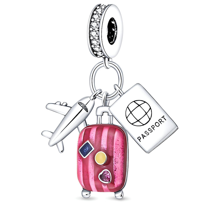Charm pendentif argent avec valise rose, passeport blanc et avion argenté, détails couleurs vives.