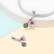 Charm argent avec volant de badminton rose et raquette détaillée, style délicat et féminin.