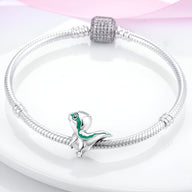 Bracelet argenté avec charm petit dinosaure vert et blanc, finition brillante.