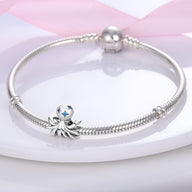 Bracelet argenté avec charm poulpe en argent orné d'étoiles bleues sur plaque blanche.