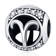 Charm rond en argent avec le symbole du bélier noir et détails en strass brillants.