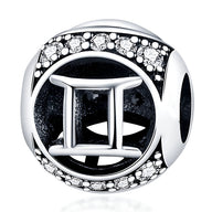 Charm rond en argent avec symbole gémeaux et contour orné de petits cristaux blancs.