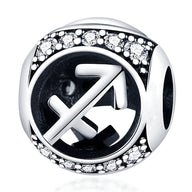 Charm rond en argent avec symbole sagittaire gravé et bordure ornée de petites pierres blanches scintillantes.