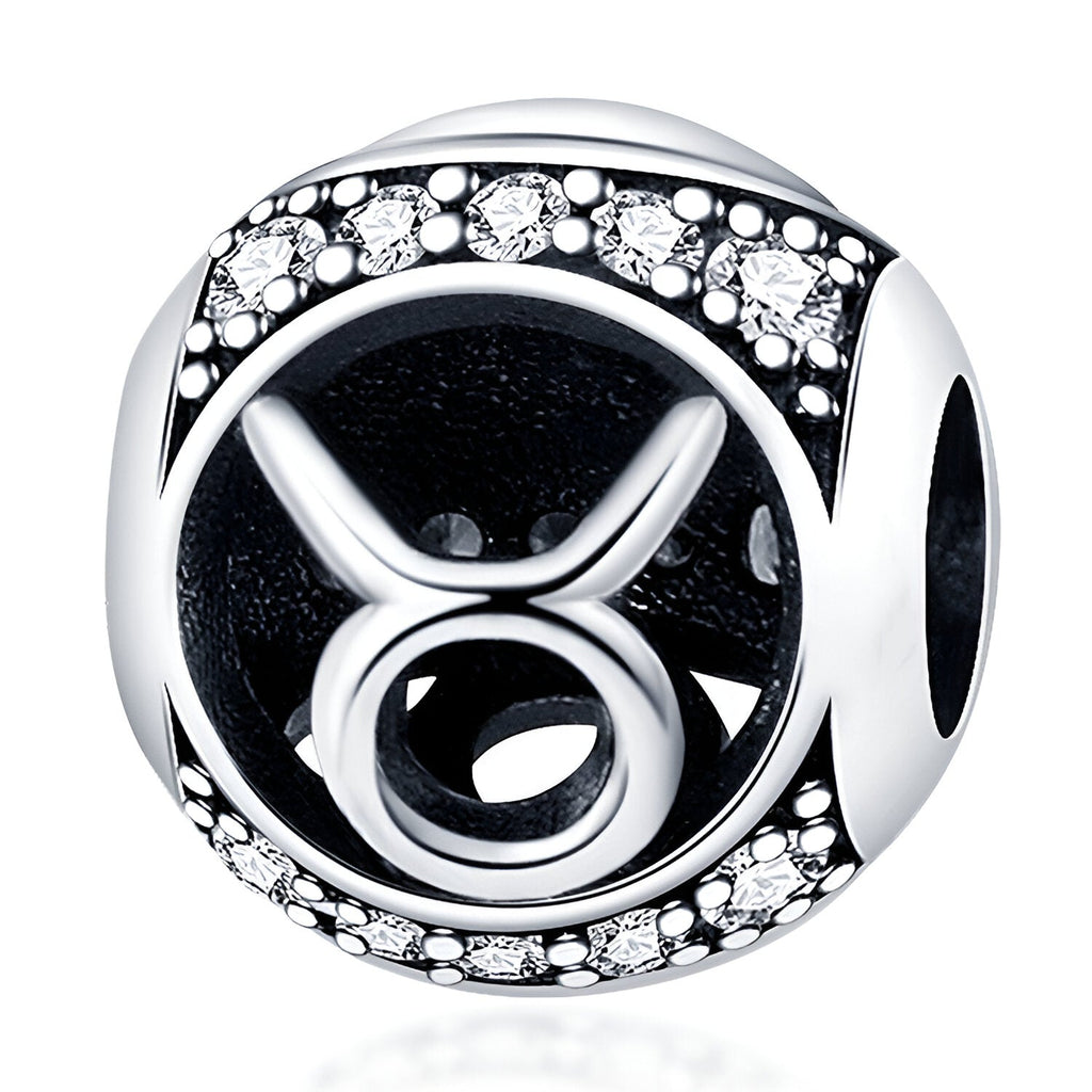 Charm rond en argent avec symbole Taureau noir et bordure ornée de petits cristaux blancs.