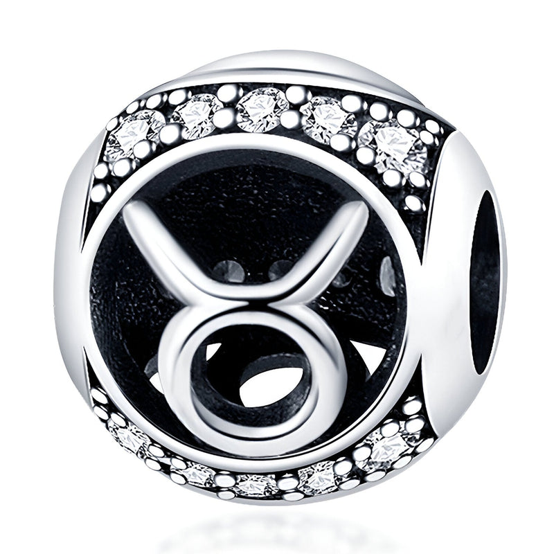 Charm rond en argent avec symbole Taureau noir et bordure ornée de petits cristaux blancs.