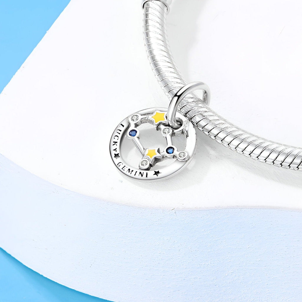 Charm rond en argent avec constellation Gémeaux, étoiles colorées et inscription Gemini.