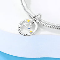 Charm rond en argent avec constellation du Taureau et étoiles jaunes, attaché à un bracelet serpent argenté.