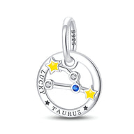 Charm rond en argent avec constellation Taureau, deux étoiles jaunes, pierres blanches et bleue, gravure "Lucky Taurus".
