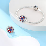 Charm tournesol en argent avec pétales bleus et rouges, monté sur bracelet serpent argenté.