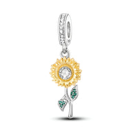 Charm pendentif tournesol doré avec pierre centrale claire et tige argentée ornée de feuilles vertes.