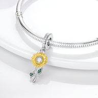 Charm argenté tournesol avec pétales jaunes émaillés et tige ornée de deux feuilles vertes sur bracelet serpent argenté.