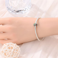 Charm argenté avec trèfle à 4 feuilles vert et coccinelle rouge sur bracelet fin argenté.
