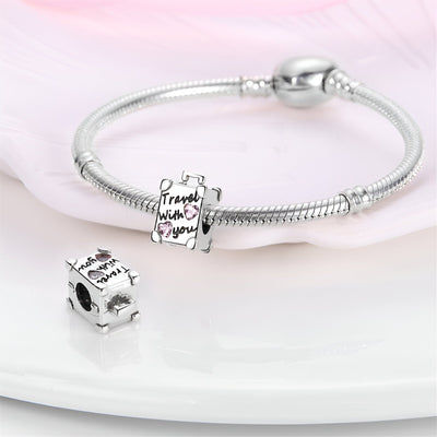 Charm valise argentée avec gravure "Travel with you" et bracelet serpent en argent brillant.
