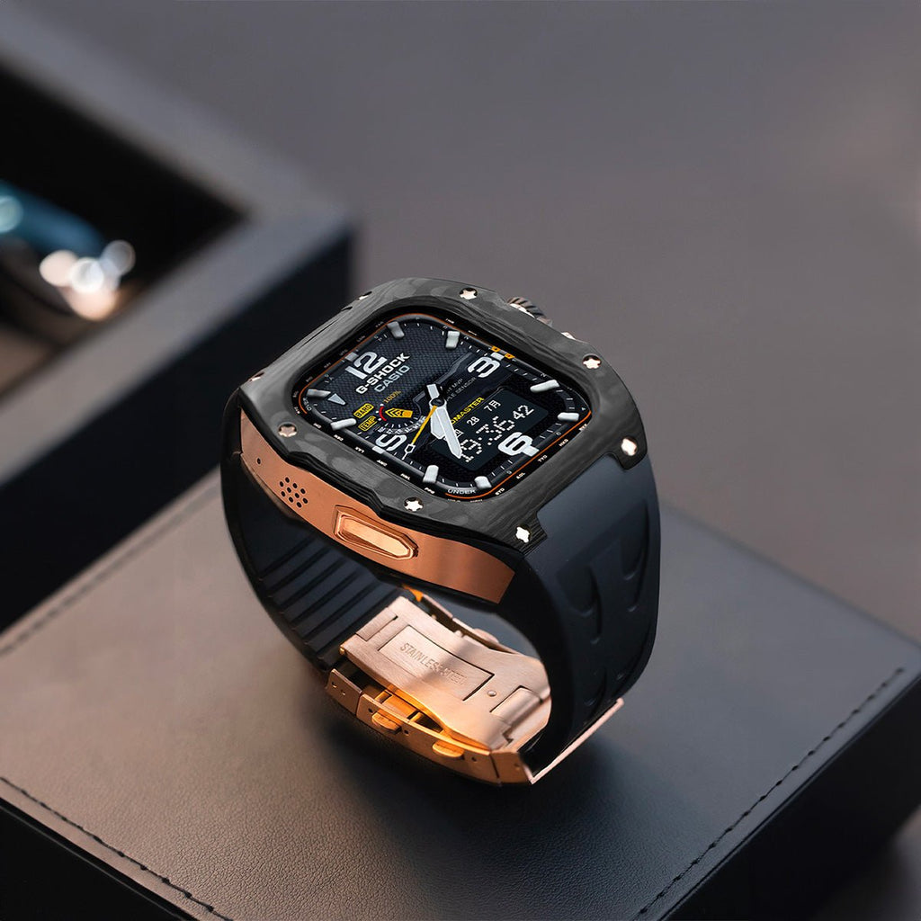 Montre Apple Watch Ultra noire avec bracelet silicone noir et boucle en acier doré, écran carré protégé par coque en fibre.