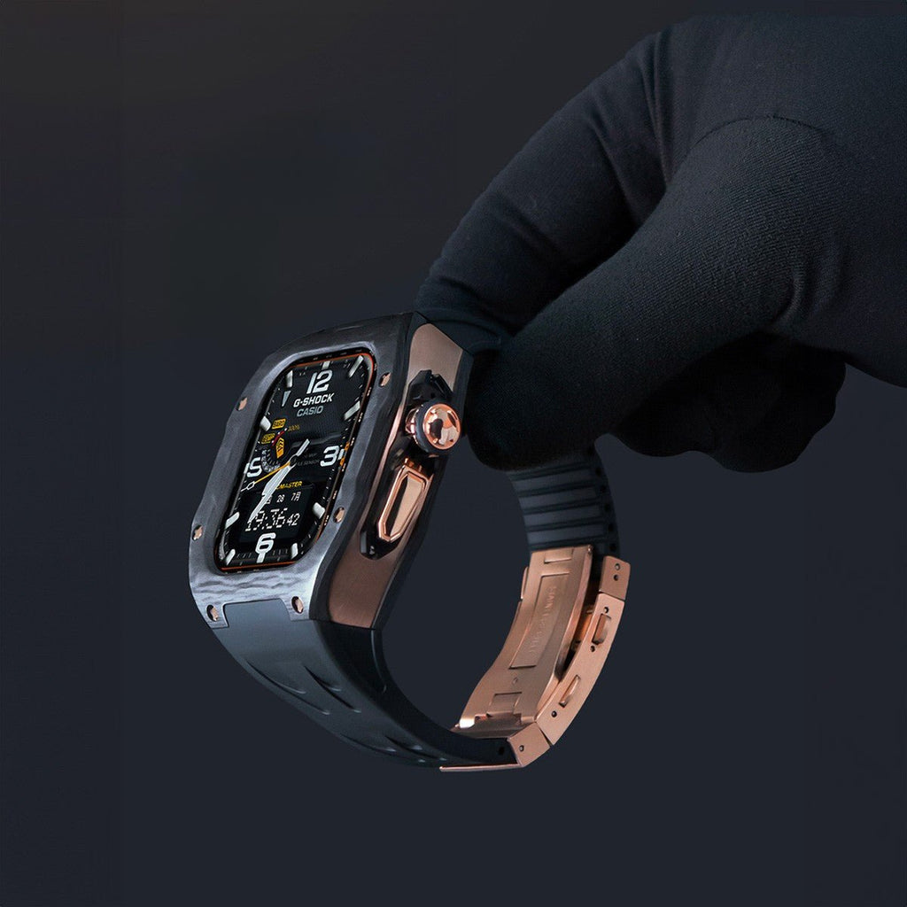 Apple Watch Ultra avec coque intégrale fibre de carbone, bracelet silicone noir et acier rose doré, design sportif élégant.