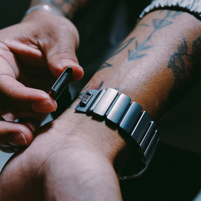 Bracelet Apple Watch en titane grade 4 gris mat avec fermoir robuste et design élégant, porté au poignet.