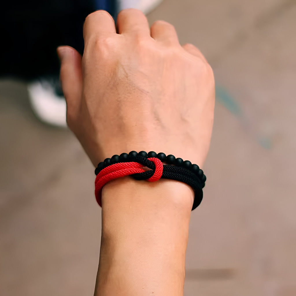 Duo de bracelets cordon rouge et noir avec perles d'onyx et nœud central noir.
