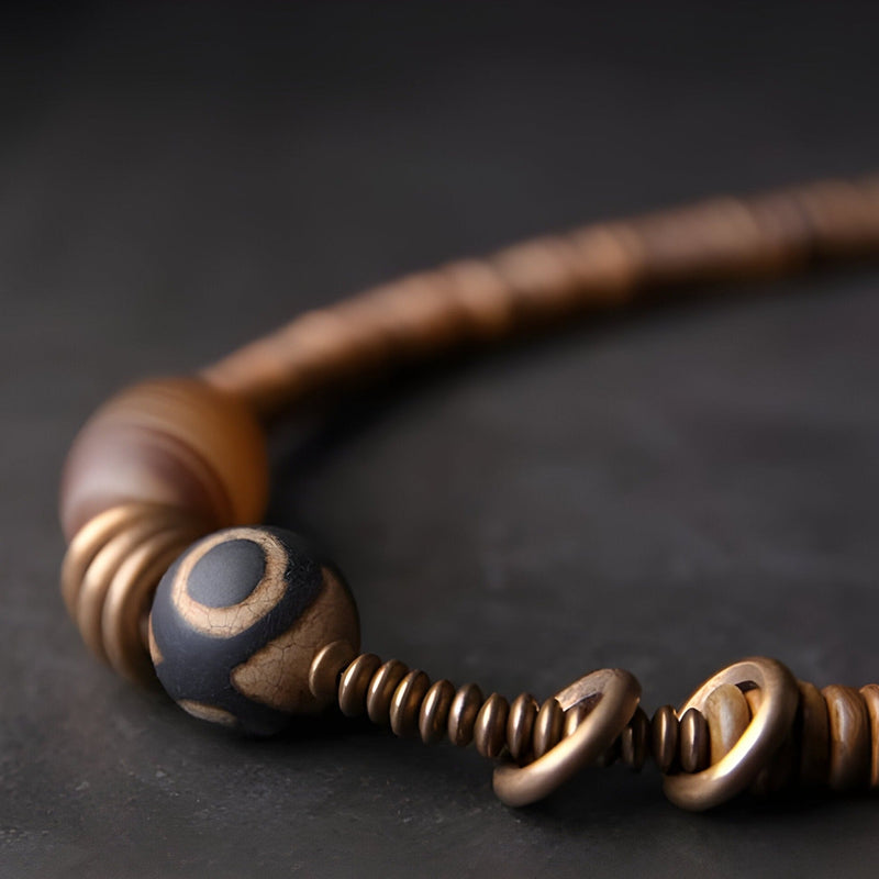 Duo de bracelets marron en bois et cuivre avec perle d'agate noire et détails torsadés.