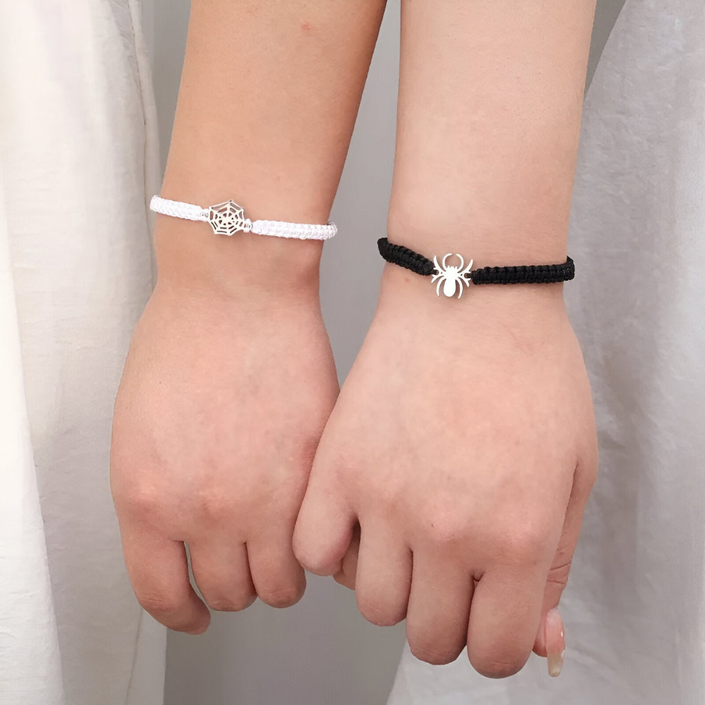 Duo de bracelets cordon blanc et noir avec pendentifs araignée argentés, style couple.