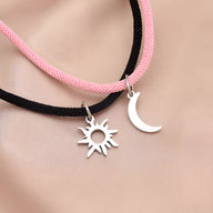 Duo de bracelets cordon rose et noir avec pendentifs soleil et lune argentés.