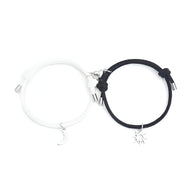 Duo de bracelets cordon blanc et noir avec pendentifs lune et soleil argentés, fermoirs réglables.